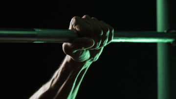 A strong hand gripping a pull-up bar, dark and editorial